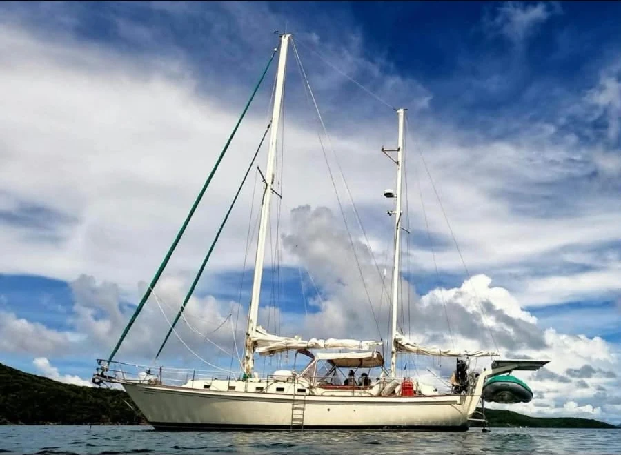 Sweet Surrender at anchor beneath a blue, cloud-filled sky
